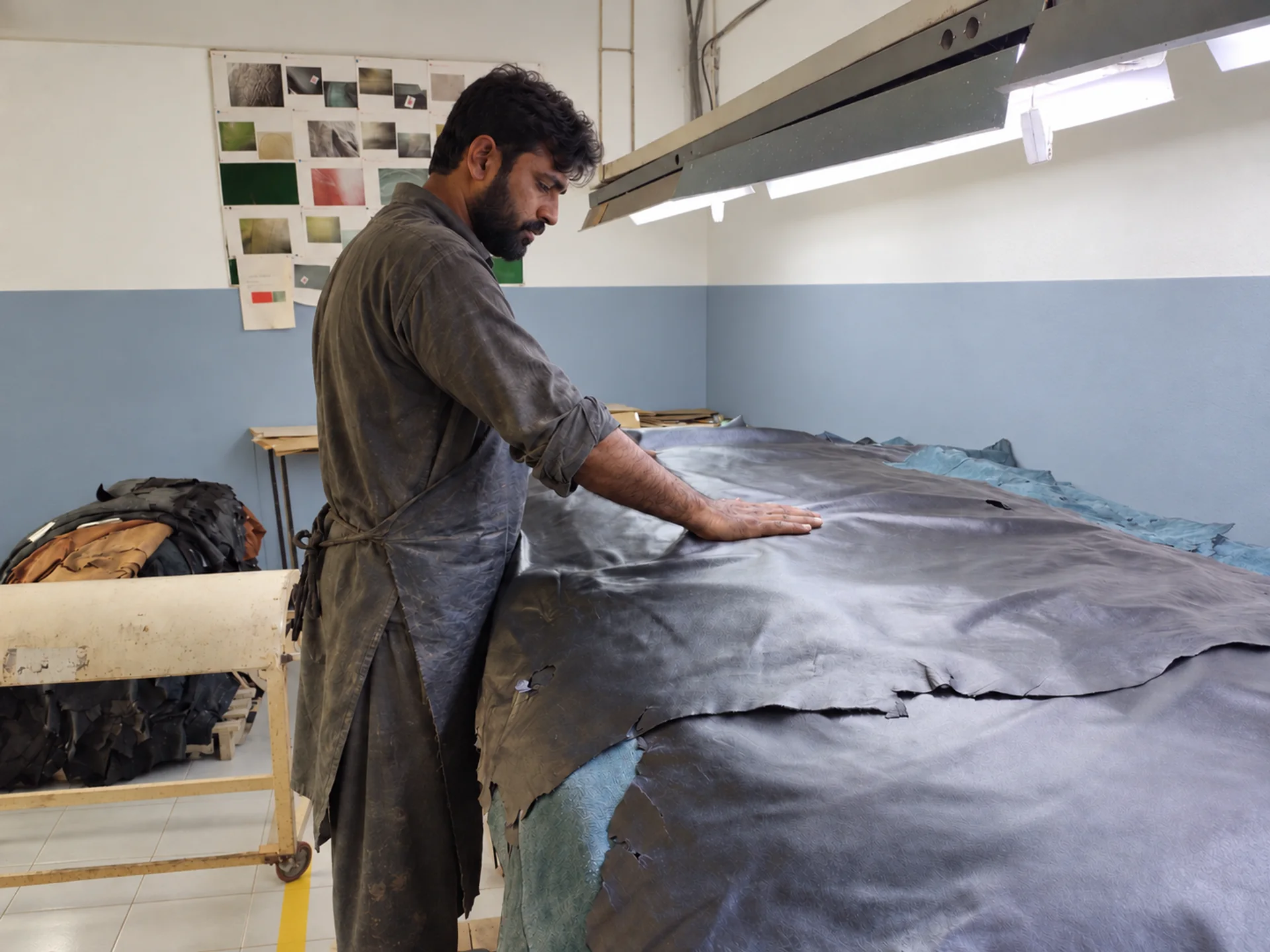 Pakistani leather specialist inspecting a hide before cutting